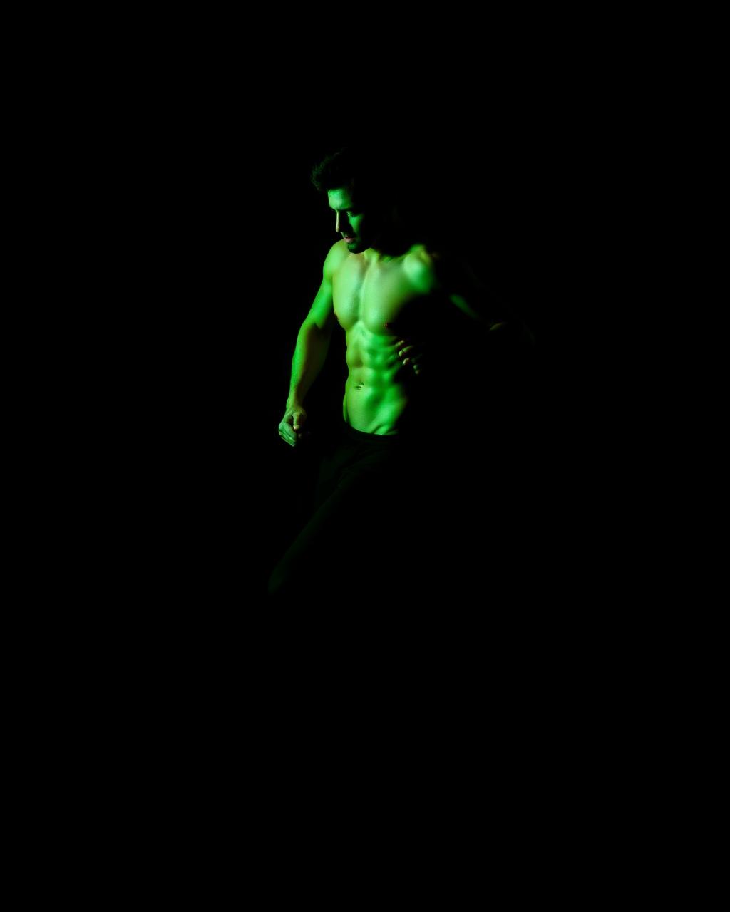 Atleta en movimiento en estudio oscuro con luz lima